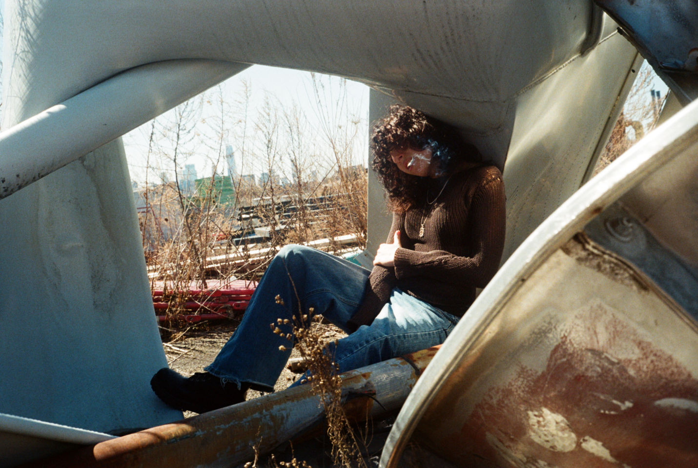 Artist Jane Remover sitting in a Junk Yard smoking a cigarette